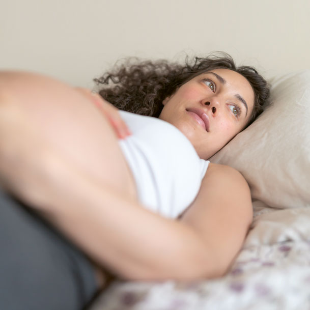 Woman in pregnancy rests on bed
