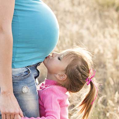 Daughter kisses mum's pregnant belly