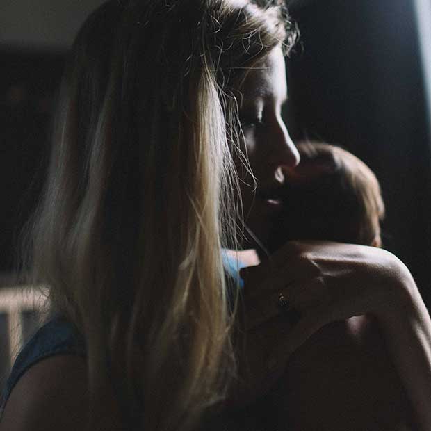 Mum holds newborn baby in dark room