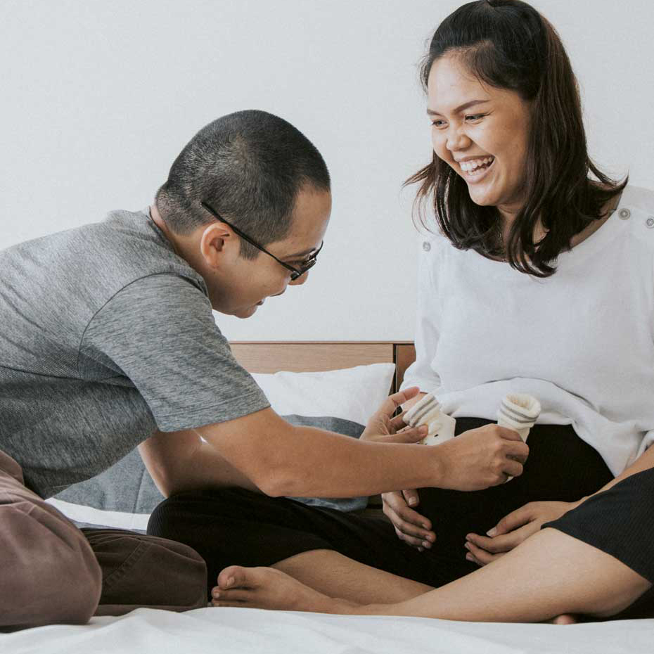 Dad puts baby shoes on mum's pregnant bump