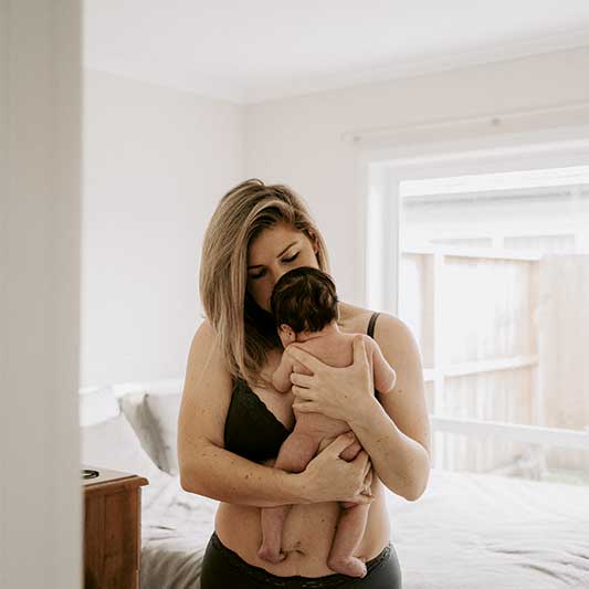 Mum holds newborn baby on chest