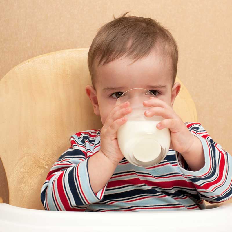 Toddler drinking cows' milk from a glass