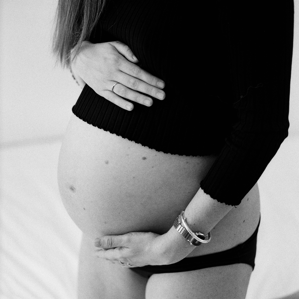 Home birth mama holds her pregnant belly