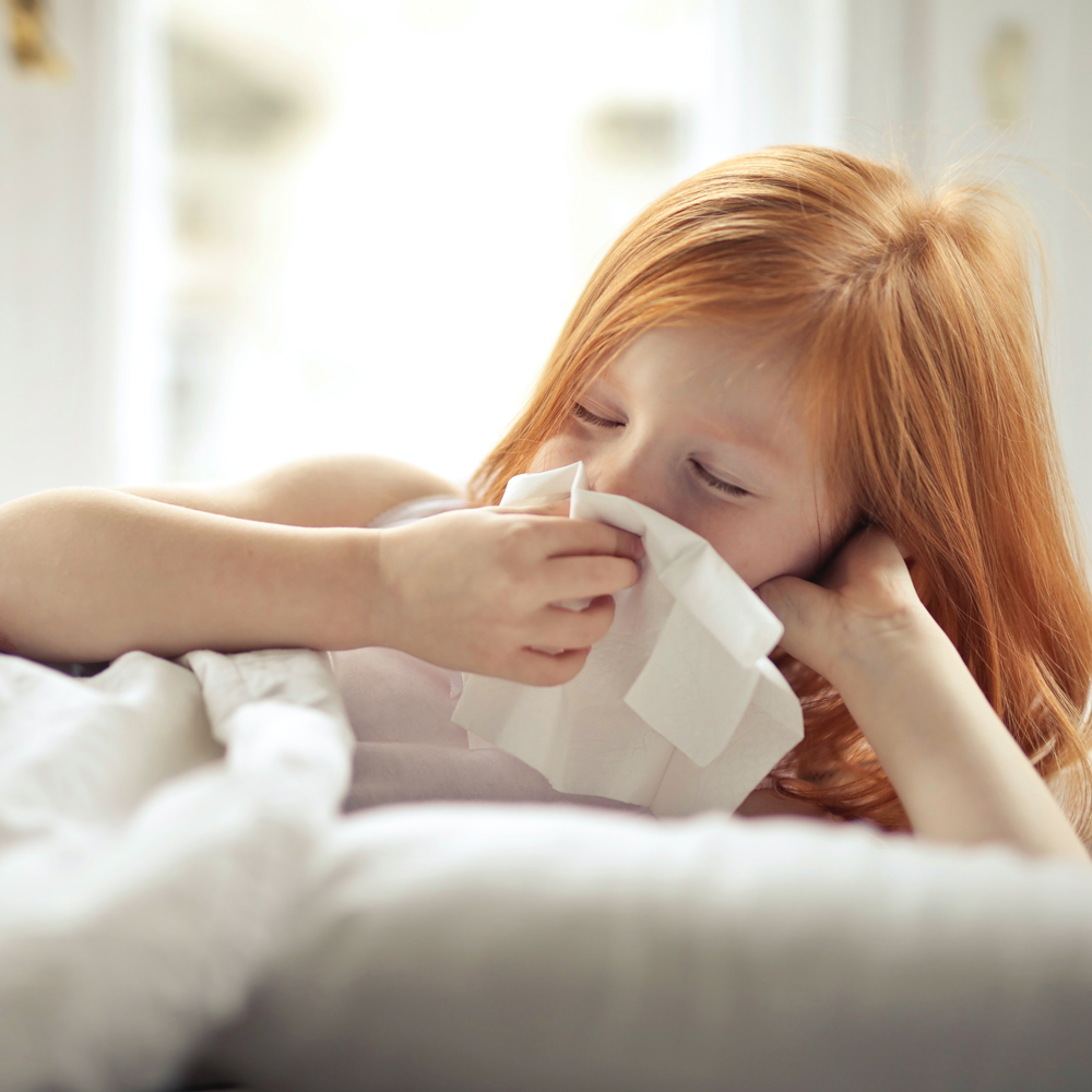 RSV in NZ: Sick child blows her nose with a tissue