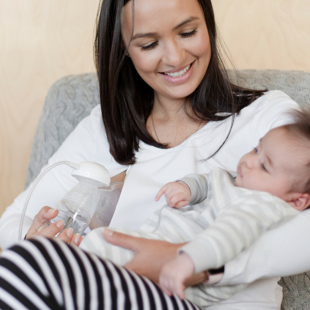 Mum pumping while holding baby