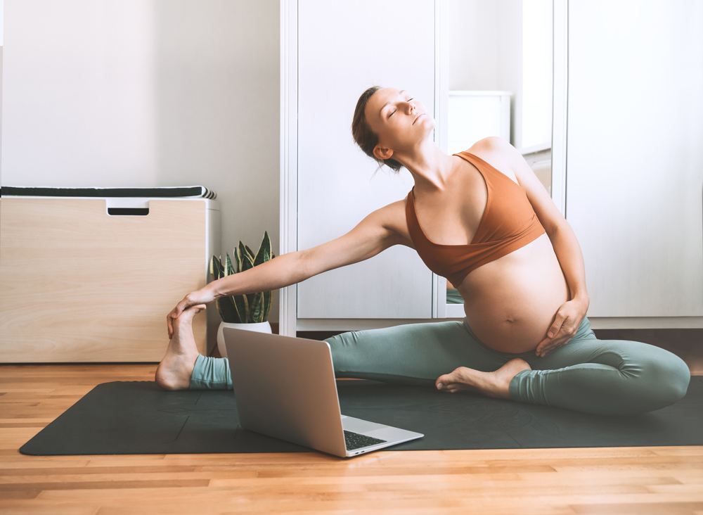 Pregnant woman doing yoga at home online