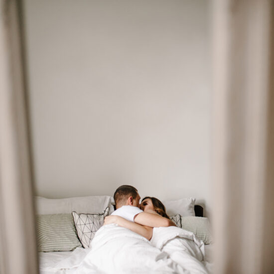 Postpartum couple kissing in bed