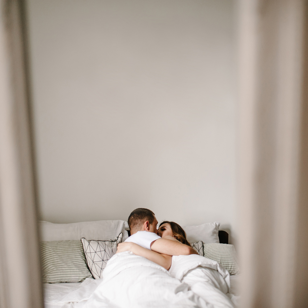 Postpartum couple kissing in bed