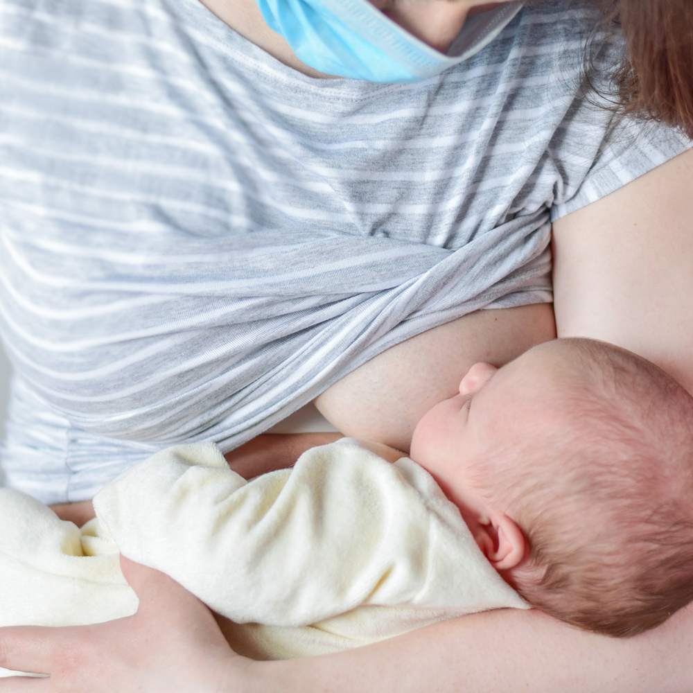 COVID-19 positive mum breastfeeding newborn baby with mask on